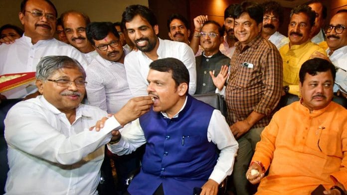 Devendra Fadnavis being fed a a sweet by Chandrakant Patil Wednesday | ANI