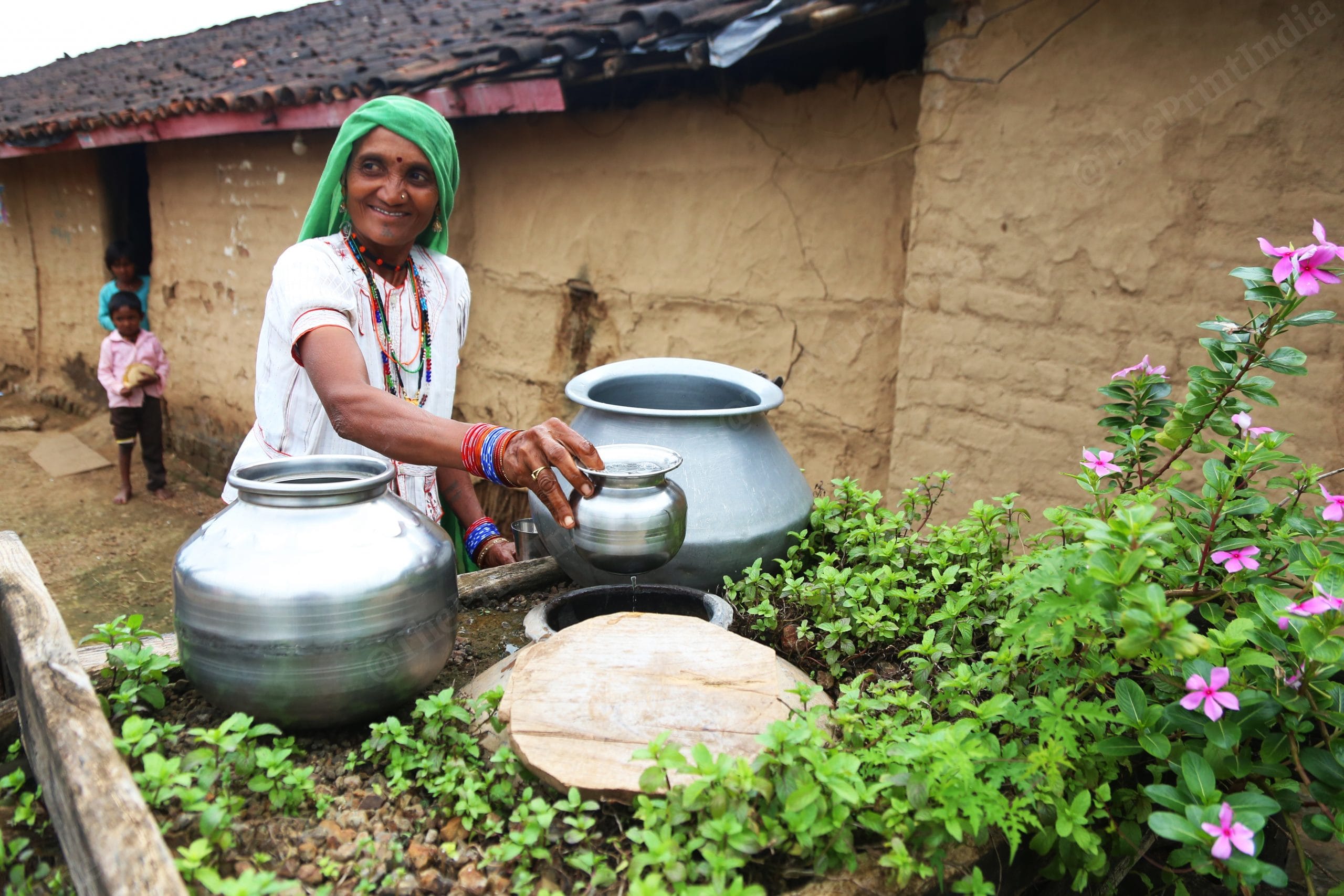 A woman poses at the personal water station build outside her house. These platforms have clay utensils filled with water kept outside surorunded by plants to keep the water cool | Manisha Mondal, ThePrint