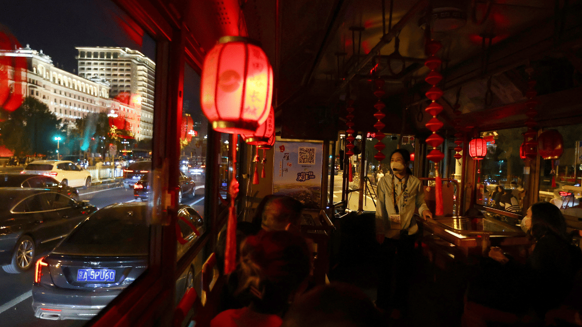 Passengers wearing face masks following the coronavirus disease (COVID-19) outbreak sit in a sightseeing bus during a night tour, ahead of the Chinese National Day Golden Week holiday in Beijing, China September 26, 2022 | REUTERS