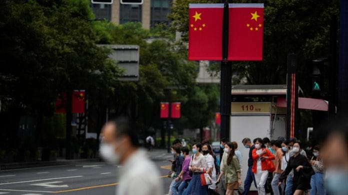 People wearing face masks crossing a street in Shanghai on 28 September 2022 | Aly Song/Reuters