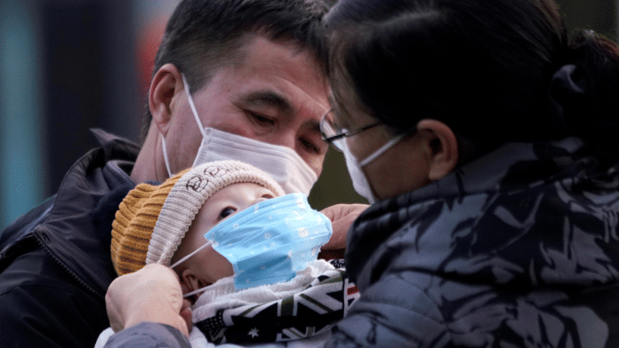 Passengers help a baby wear a mask at the Shanghai railway station in China, as the country is hit by an outbreak of the novel coronavirus | Reuters/Aly Song/