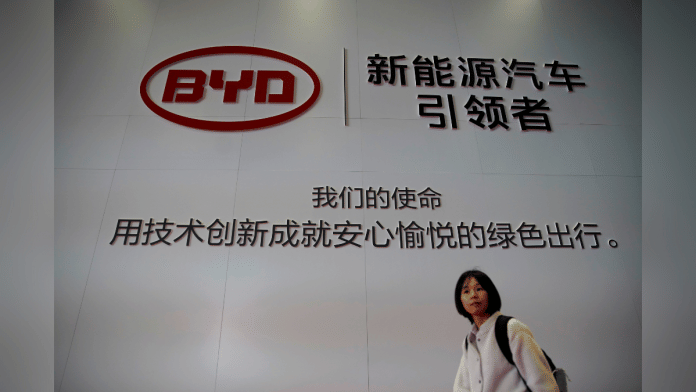 FILE PHOTO: A woman walks past a BYD sign at the second media day for the Shanghai auto show in Shanghai, China April 17, 2019. REUTERS/Aly Song