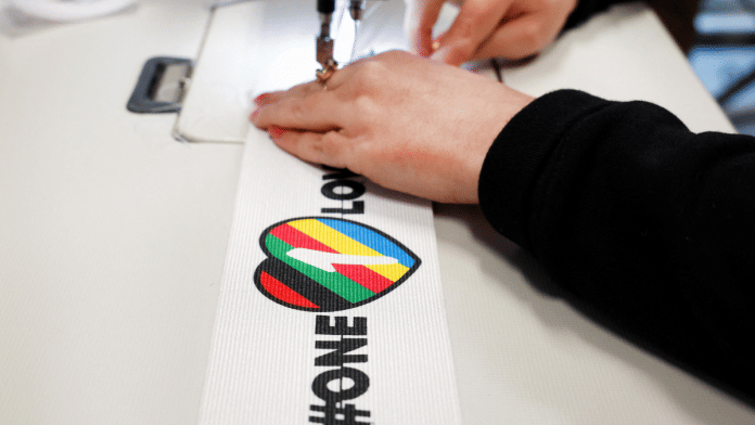A woman sews Velcro on to a One Love armband, which is banned by FIFA at the World Cup Qatar 2022 | Reuters Photo