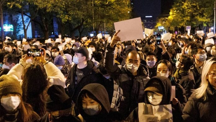 People hold white sheets of paper in protest of Covid restrictions in Beijing, on 27 November 2022 | Reuters/Thomas Peter
