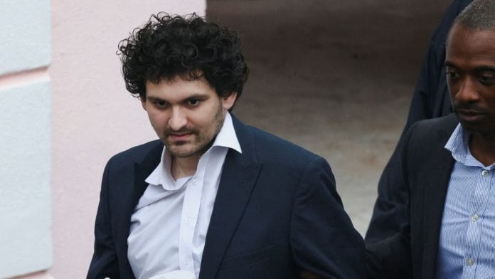 Sam Bankman-Fried, the founder and former CEO of crypto currency exchange FTX, is escorted out of the Magistrate Court building in Nassau, Bahamas, 21 December 2022 | Reuters/Dante Carrer