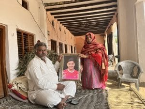 Vikrant Som's parents holding his framed photo in their verandah | Jyoti Yadav, ThePrint