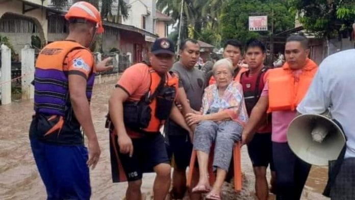 Rescue workers helps a resident affected by floods, in Plaridel, Misamis Occidental Province, Philippines, 26 December 2022. Philippine Coast Guard/Handout via Reuters