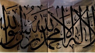 A Taliban supporter holds an Islamic Emirate of Afghanistan flag