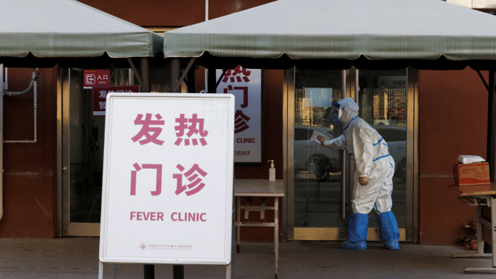 A health worker in a protective suit wipes the door to a fever clinic at a hospital as coronavirus disease outbreaks continue in Beijing | Reuters Photo/Thomas Peter