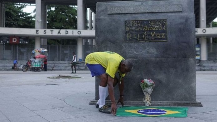 Marcio Pereira da Silva, known as Pele, a street artist, lays down a Brazilian flag in front of Maracana Stadium as people mourn the death of Brazilian soccer legend Pele, in Rio De Janeiro, Brazil, 29 December | Reuters/Ricardo Moraes