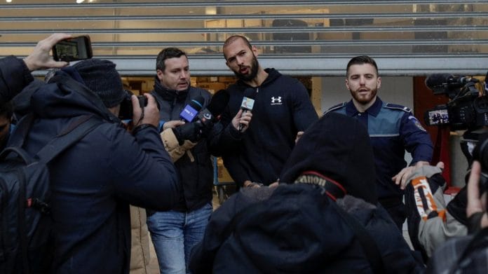 Andrew Tate answers questions from the media while being escorted by police officers in Bucharest, Romania, on 25 January 2023 | Inquam Photos/Octav Ganea via Reuters