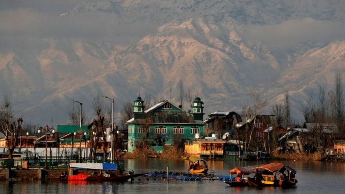 People row their boats in the waters of Dal Lake with the backdrop of snow-covered mountains after a snowfall in Srinagar | Reuters file photo/Danish Ismail