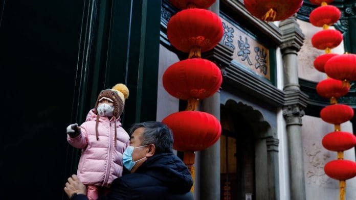 An elderly person holds a child near lanterns decorating a shop ahead of the Chinese Lunar New Year, in Beijing, China, 15 January 15, 2023 | Reuters