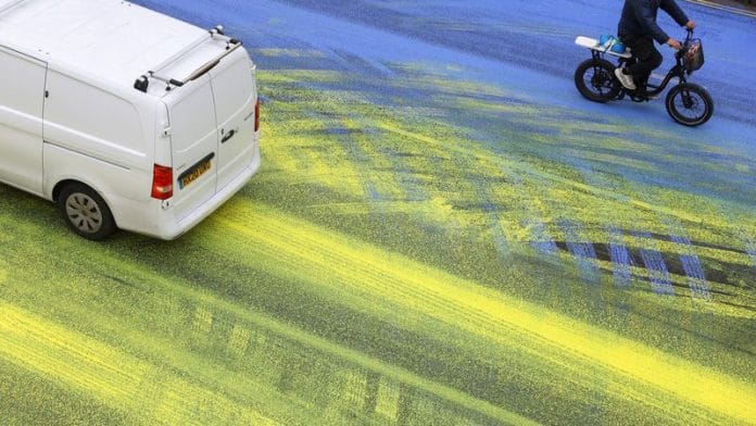 A cyclist rides on a painted road, after Protest group 'Led by Donkeys' spread paint in the colours of the Ukrainian flag on the road, ahead of the first anniversary of Russia's invasion of Ukraine, outside the Russian Embassy in London on 23 February | Reuters