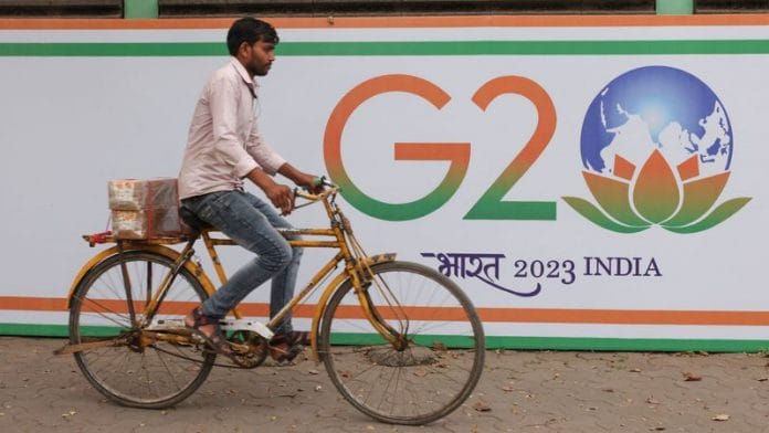 A man rides a bicycle past the hoarding of India's G20 presidency, on a street in Mumbai on 15 December, 2022 | Reuters