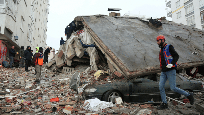A man standing amid rubble looks at the damage following an earthquake in Hatay, Turkey, 7 February 2023 | Reuters/Umit Bektas