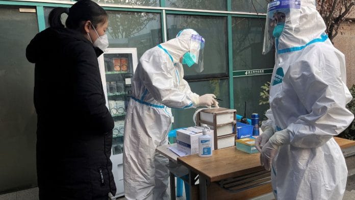 File photo of a medical worker in a protective suit registering information for a patient at the entrance to the fever clinic of the Central Hospital of Wuhan in Wuhan, Hubei province, China on 31 December, 2022 | Reuters