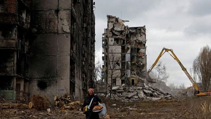 File photo of a woman walking through her neighbourhood & past apartment blocks that were destroyed in the course of Russia-Ukraine conflict in Mariupol, Russian-controlled Ukraine, on 15 February 2023 | Reuters
