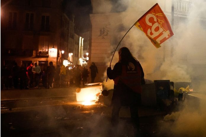 A demonstrator holds a CGT labour union flag during a protest on 16 March, 2023 | Reuters