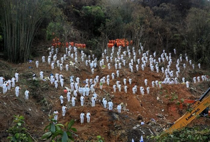 Rescue workers stand in a silent tribute at the site to mourn the victims of a China Eastern Airlines Boeing 737-800 plane, flight MU5735, that crashed in Wuzhou on 27 March 2022 | Photo: Reuters