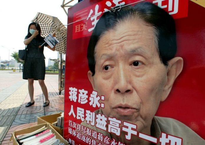 Chinese woman adjusts her facemask at newspaper stall featuring a photo of Dr. Jiang Yanyong in Beijing |Reuters photographer