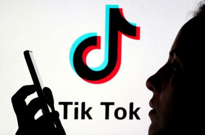 A person holds a smartphone as Tik Tok logo is displayed behind in this picture illustration | Reuters