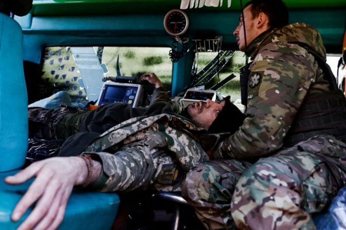A wounded Ukrainian soldier reacts as he is treated by medics inside a frontline stabilisation ambulance in an undisclosed location near the frontline town of Kreminna, Ukraine on 13 March 2023 | Photo: REUTERS