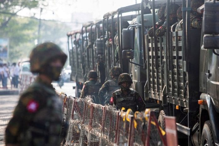 Soldiers stand next to military vehicles as people gather to protest against the military coup, in Yangon, Myanmar | File Photo: Reuters