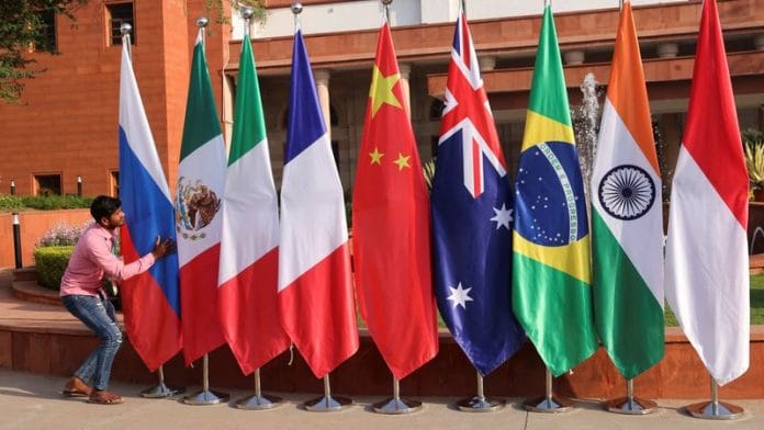 A man arranges the flags kept outside the venue for G20 foreign ministers’ meeting in New Delhi on 2 March, 2023 | Reuters