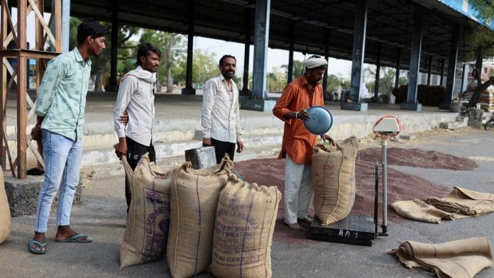 File photo of a man measuring harvested rapeseed crops inside a sack on a weighing machine in a market yard in Niwai, on 23 February, 2023 | Reuters