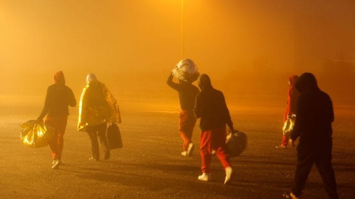 FILE PHOTO: French policemen stand beside a dinghy lying on the beach after migrants tried to start the engine of a rubber dinghy they wanted to use to leave the coast of northern France and to cross the English Channel, in Sangatte near Calais, France, November 29, 2022. REUTERS/Pascal Rossignol/File Photo