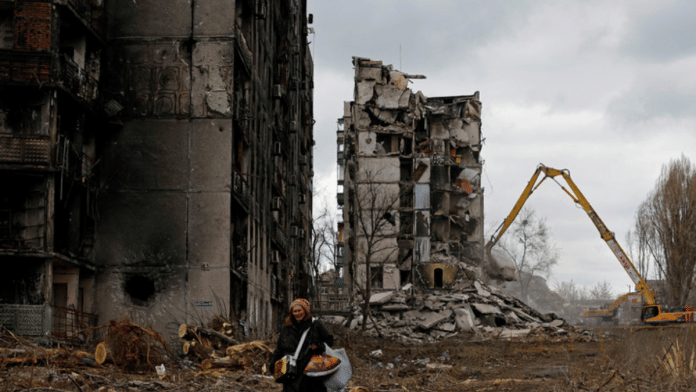 A woman reacts as she walks through her neighbourhood past apartment blocks destroyed in the course of Russia-Ukraine conflict in Mariupol | Reuters file photo