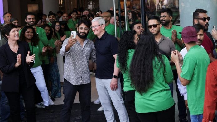 A man takes a picture with Apple CEO Tim Cook during the inauguration of India's first Apple retail store in Mumbai, on 18 April 2023 | Reuters