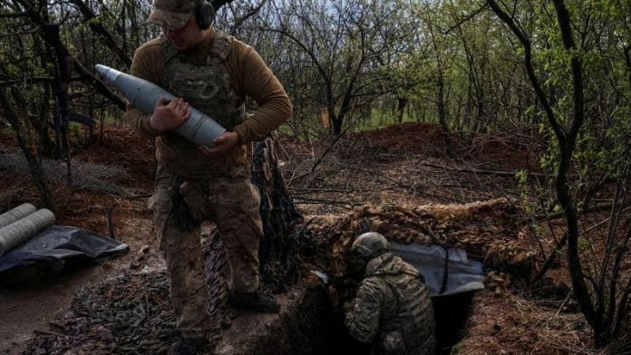 A Ukrainian service member from a 3rd separate assault brigade of the Armed Forces of Ukraine, carries a shell as they prepare to fire a howitzer D30 at a front line, amid Russia's attack on Ukraine, near the city of Bakhmut on 23 April, 2023 | Reuters