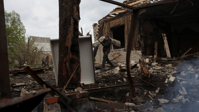 A neighbour carries items from a house destroyed by a Russian drone strike in the village of Malotaranivka in Donetsk region, Ukraine | Reuters/Sofiia Gatilova