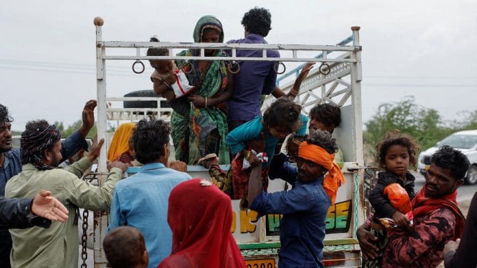 A man carries a child from a truck during an evacuation before the arrival of cyclone Biparjoy in Jakhau in the western state of Gujarat | Reuters