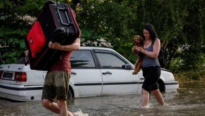 Local residents carry their personal belongings on a flooded street, after the Nova Kakhovka dam breached, amid Russia's attack on Ukraine, in Kherson, Ukraine on 6 June, 2023 | Reuters