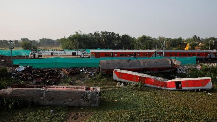 A train moves past damaged coaches after the tracks were restored, at the site of a train collision following the accident in Balasore, Odisha, on 5 June 2023 | Reuters/Adnan Abidi