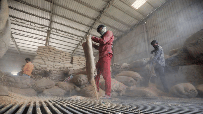 Workers empty wheat sacks for sifting at a grain mill on the outskirts of Ahmedabad/File Photo by Reuters
