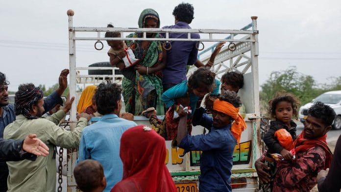 A man carries a child from a truck during an evacuation before the arrival of cyclone Biparjoy in Jakhau in the western state of Gujarat, June 14, 2023 | Reuters/Francis Mascarenhas