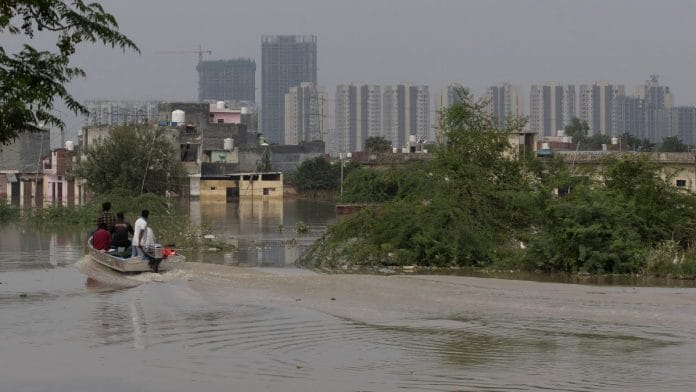 People ride a boat to look for strandad residents at a flooded colony, after a rise in waters of the river Yamuna due to heavy monsoon rain, in New Delhi | Reuters