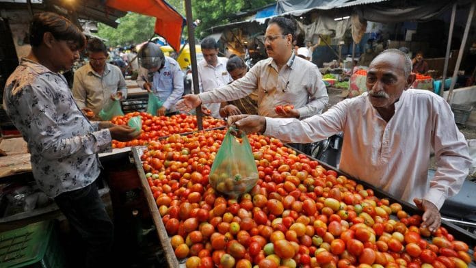 People buy tomatoes from a vendor at a vegetable market in Ahmedabad, India | Reuters