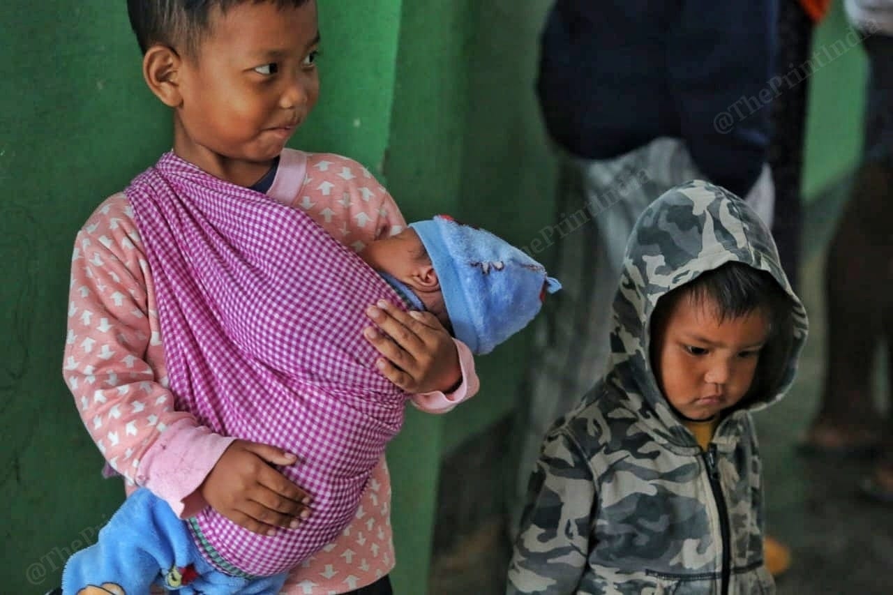 A kid holds wraps his brother, smiling, still oblivious of the tense situation in the state Photo: Praveen Jain | ThePrint
