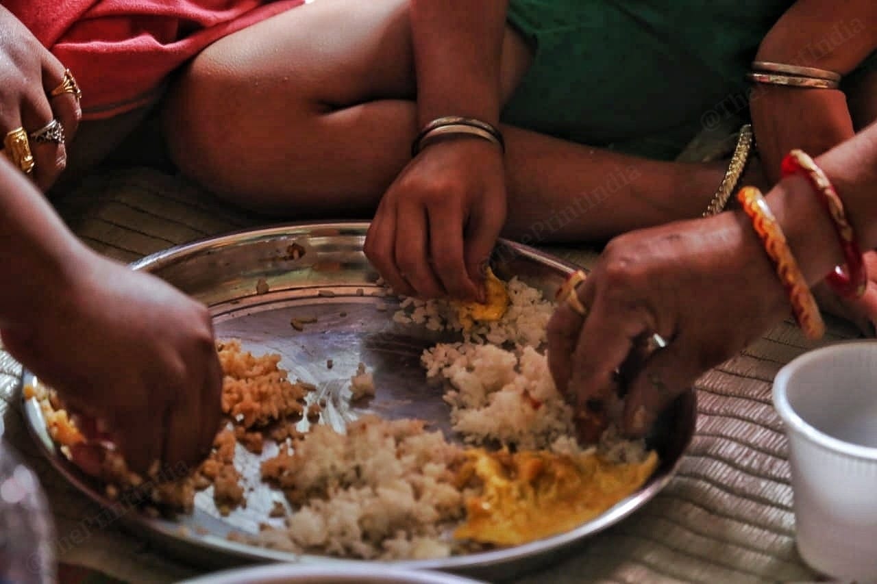Families at the camp eat from the same plate | Photo: Praveen Jain | ThePrint