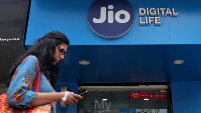 Representational Image | A woman checks her mobile phone as she walks past a Reliance Industries' Jio store in Mumbai, India | Reuters/Shailesh Andrade/File Photo