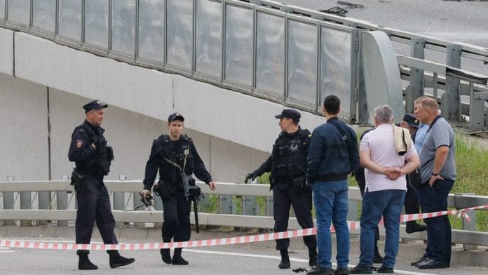 A police officer carries debris to the members of the security services investigating a bridge near the site of a damaged building following a reported drone attack in Moscow, Russia, July 24, 2023/Reuters