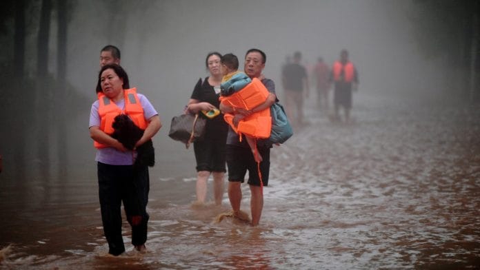 Residents wade through floodwaters following heavy rainfall in Zhuozhou, Hebei province, China | Reuters