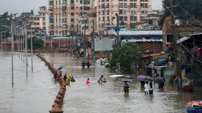People walk along a flooded road along the bank of overflowing Bagmati river following heavy rains, in Kathmandu, Nepal | Reuters