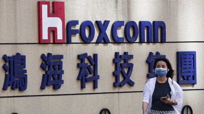 A woman walks past the logo of Foxconn outside the company's building in Taipei, Taiwan November 9, 2022 | Reuters