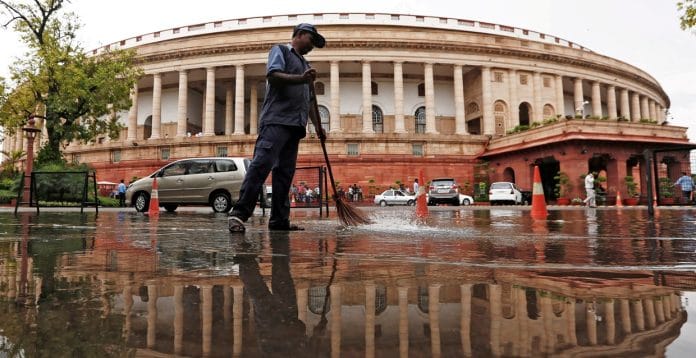 Parliament building is reflected in a puddle after the rain as a man sweeps the water in New Delhi, India July 20, 2018 | Reuters